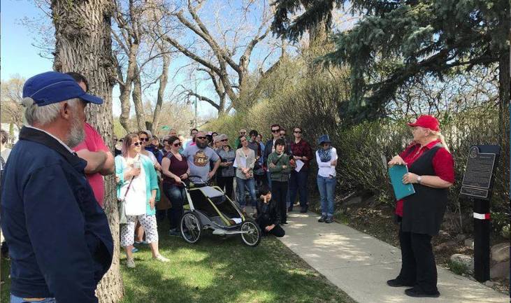 People standing outside listening to a woman as part of a Jane's Walk event.