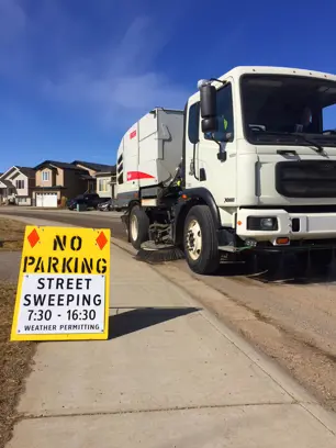 Street sweeping truck with sign that reads no parking