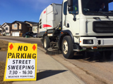 Street sweeping truck with sign that reads no parking