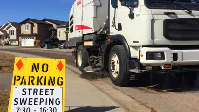 Street sweeping truck with sign that reads no parking